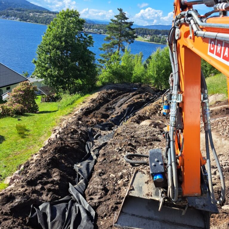 Gravemaskin ved en utgravd grøft på en boligtomt