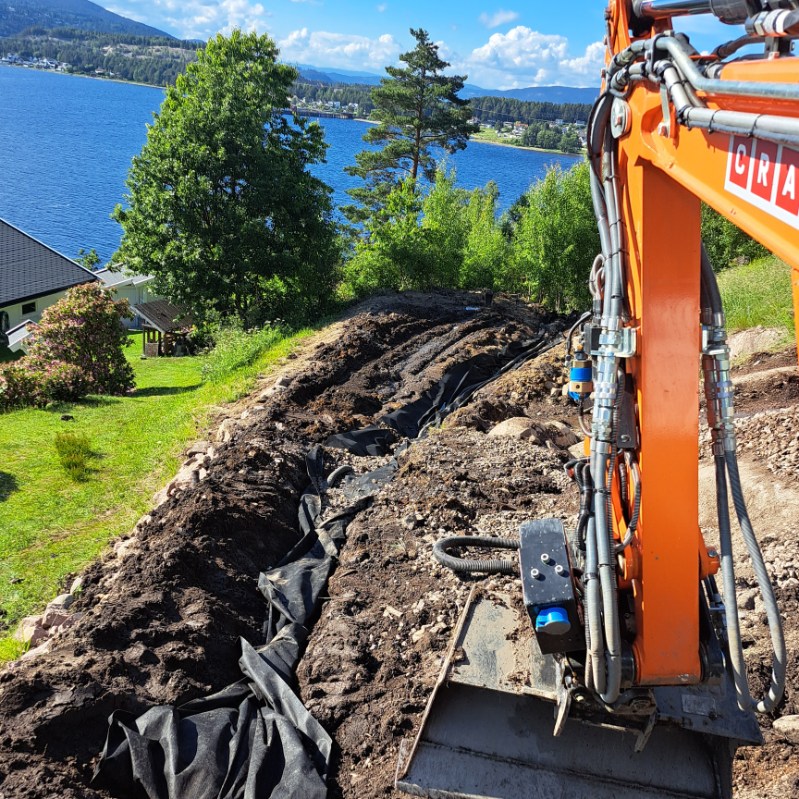 Gravemaskin ved en utgravd grøft på en boligtomt